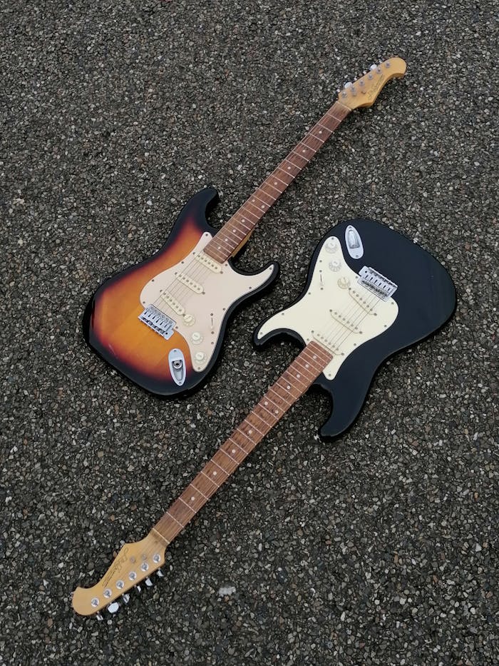 get-in-touch Close-up of two electric guitars resting on a textured concrete surface.
