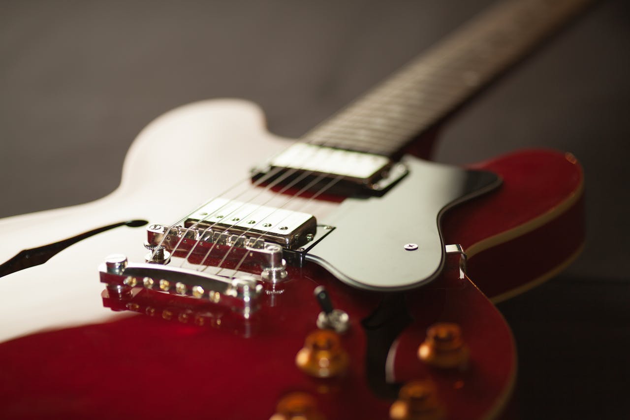 who-we-are Detailed close-up of a red electric guitar showcasing the bridge and strings.