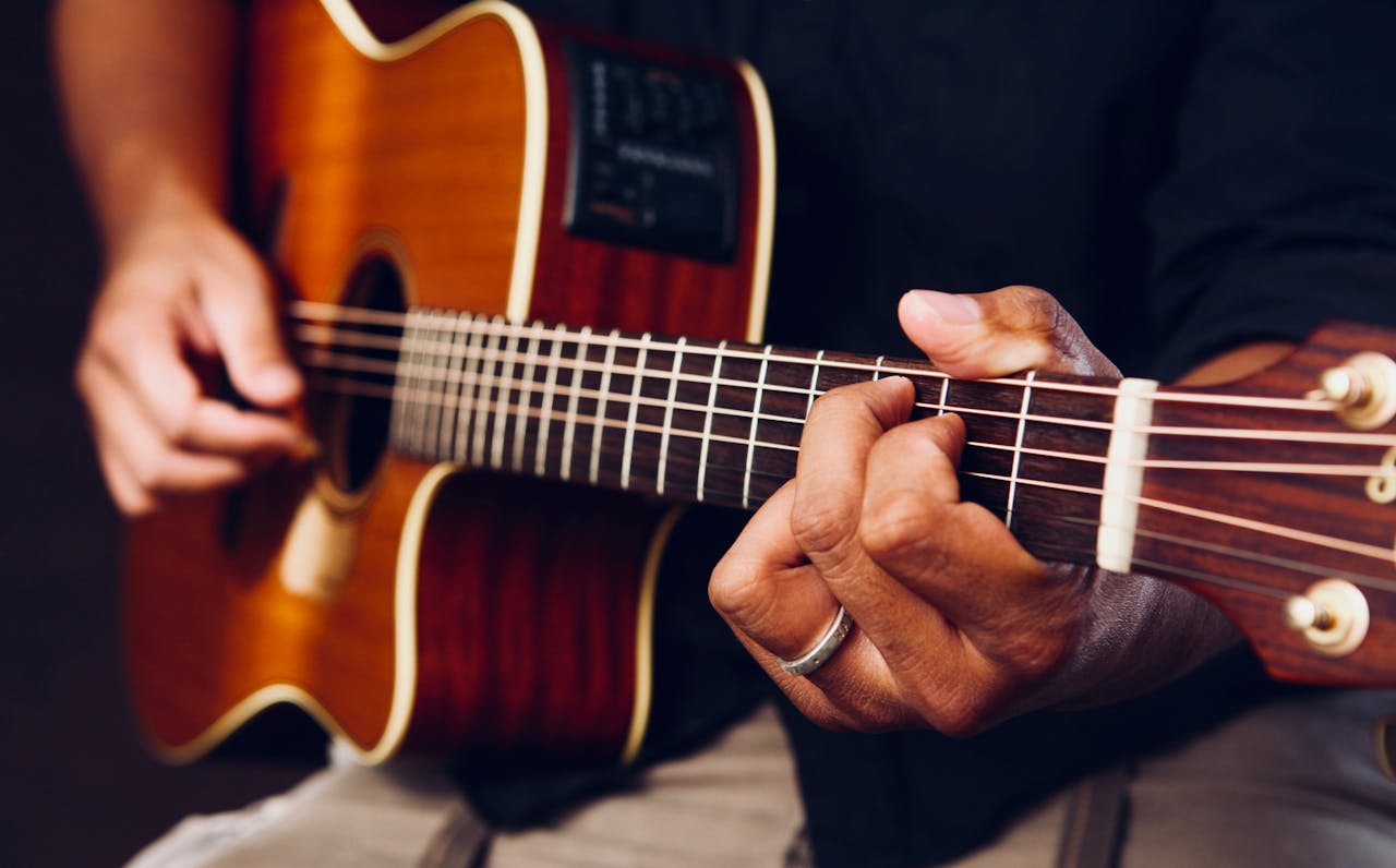 about-bg Hands playing an acoustic guitar, showcasing chords and frets up close.